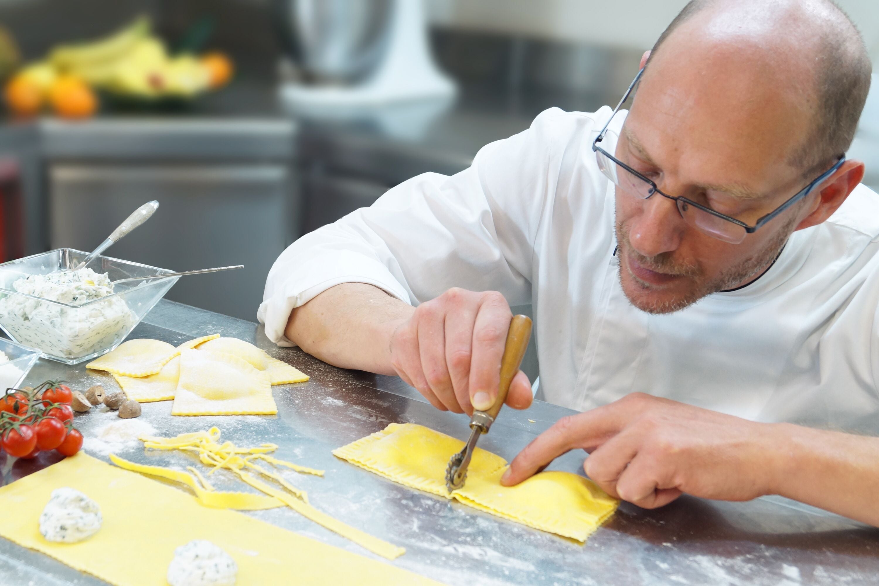 Una persona preparando comida, cortando y dando forma a la masa sobre una mesa.