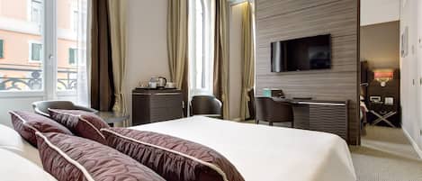 A hotel room with a large bed, a desk, a chair, a television, and a window with curtains.