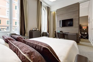 A hotel room with a large bed, a desk, a chair, a television, and a window with curtains.