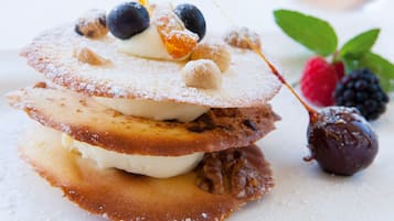 Une pile de crêpes garnie de myrtilles, de sucre glace et d’une boule de chocolat.