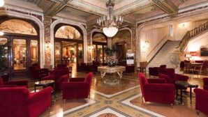 A grand lobby with red upholstered seating, a central ornate table, and a staircase. - Grand Hotel Plaza (Rome)
