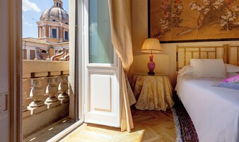 Una camera d'albergo con un balcone, un letto, un tavolo con una lampada e un quadro appeso al muro.