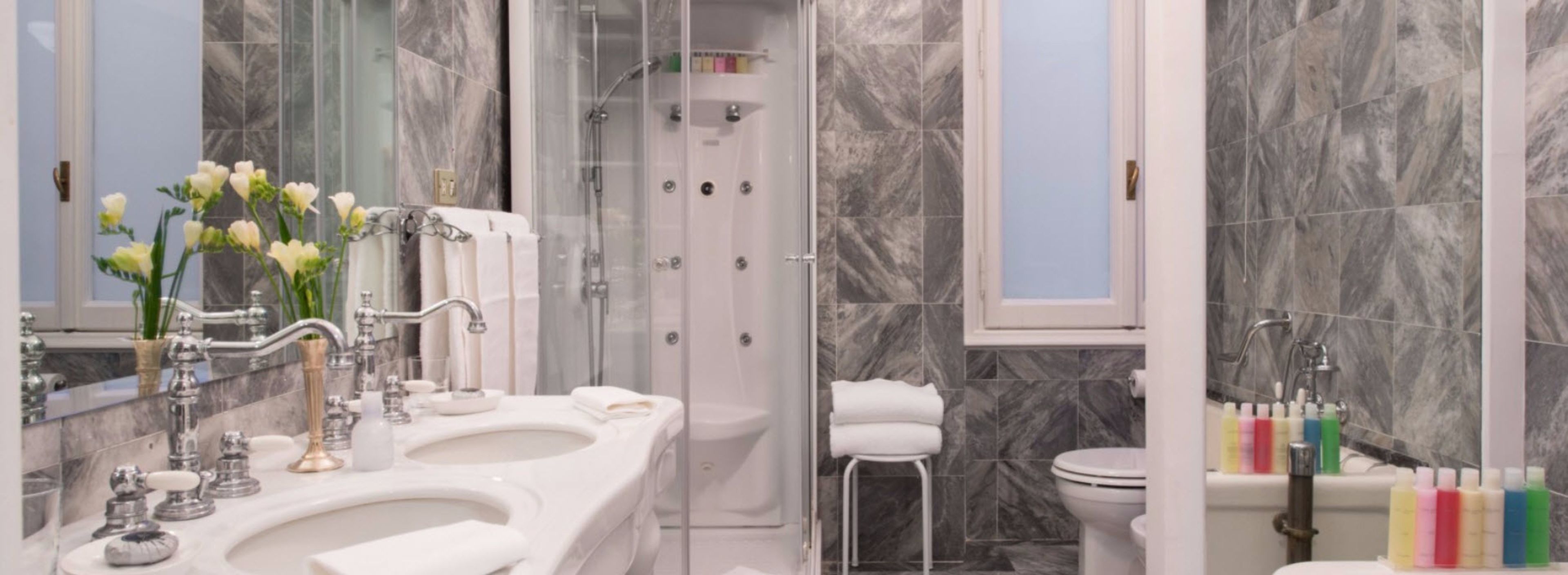 A modern bathroom with a glass-enclosed shower, a double sink vanity, and a toilet.