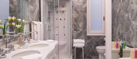 A modern bathroom with a glass-enclosed shower, a double sink vanity, and a toilet.