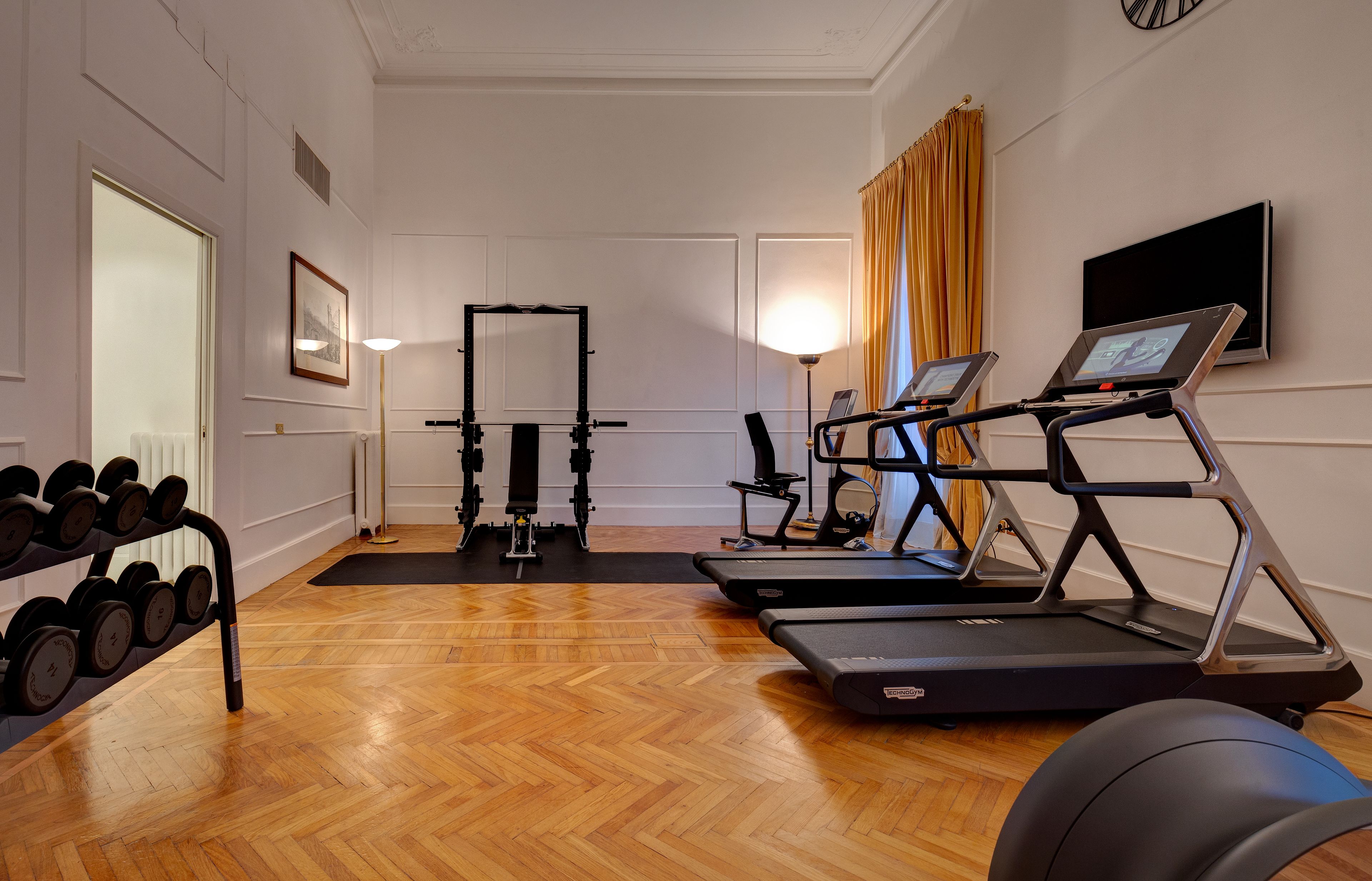 A gym with exercise equipment including dumbbells, a treadmill, and a stationary bike.
