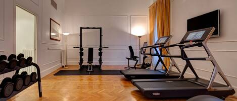 A gym with exercise equipment including dumbbells, a treadmill, and a stationary bike.