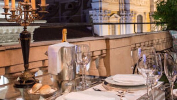 A table set for dining with a view of a historic building with a dome and columns. - Grand Hotel Plaza (Rome)