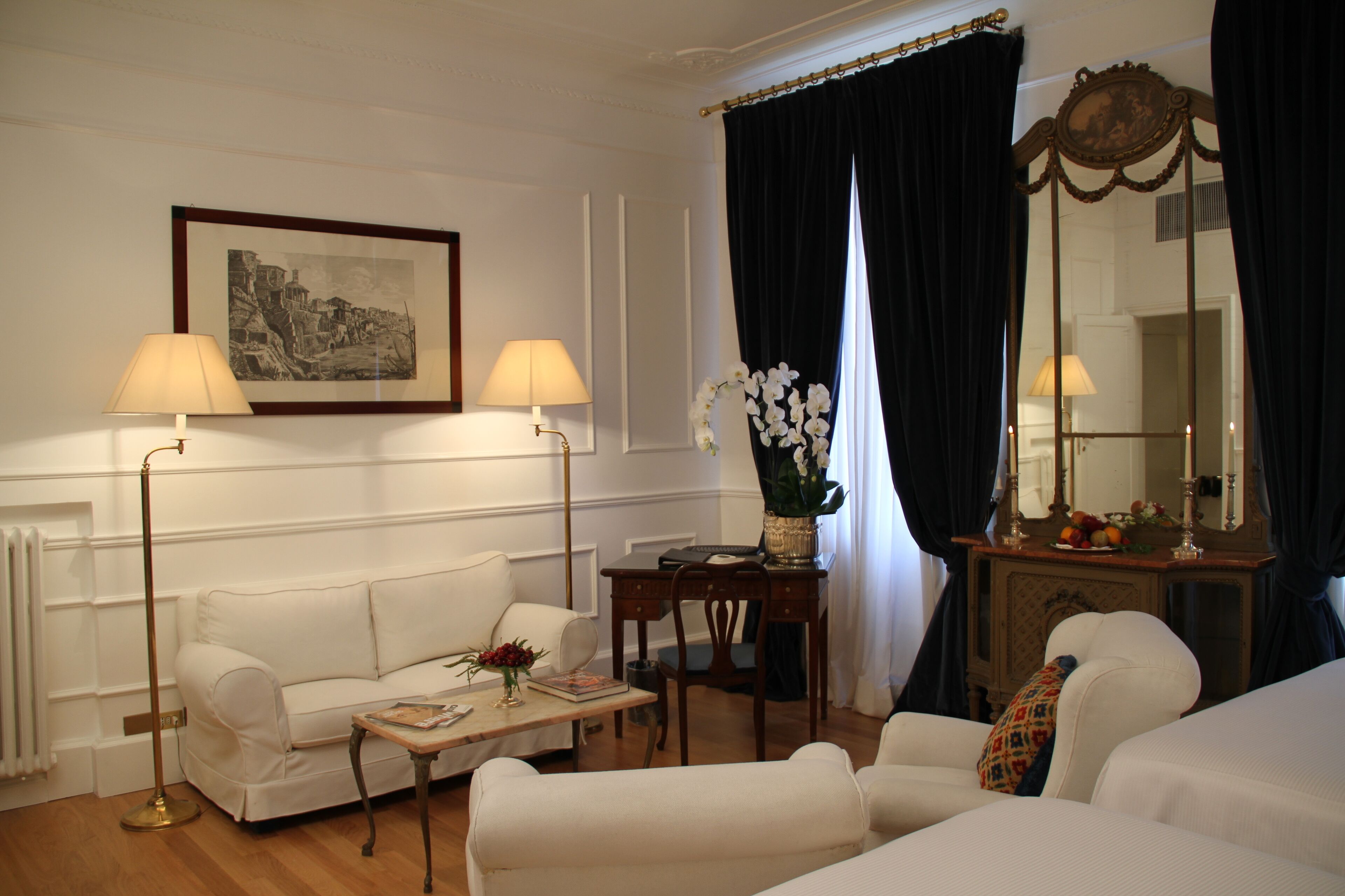 Een goed verlichte kamer met een witte bank, een houten salontafel, een bureau en een grote spiegel.