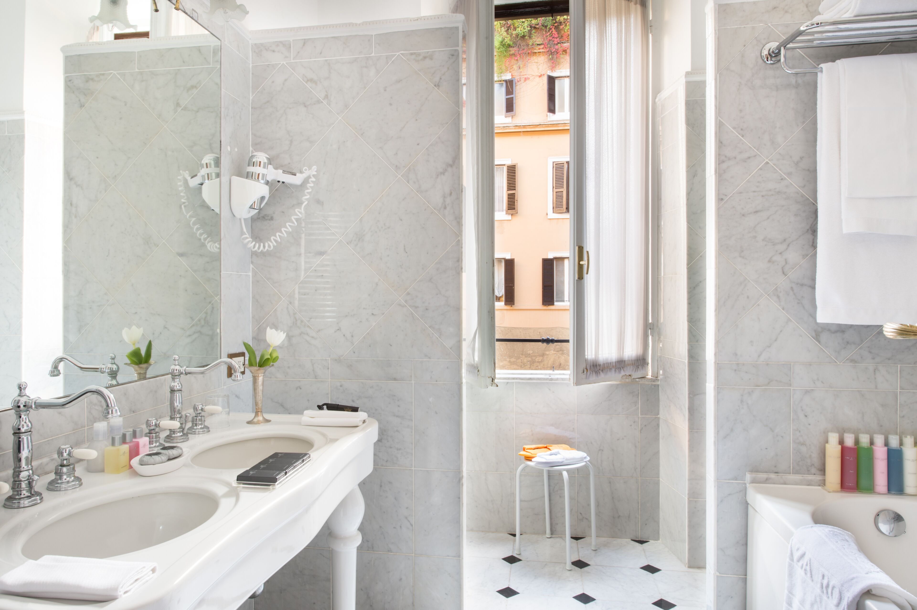 A modern bathroom with two sinks, a large mirror, and a view of the outside through a window.