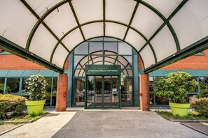 Entrada de un edificio con un arco verde y un letrero que dice "Albergo della Rotonda".