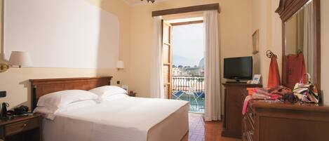 A hotel room with a bed, a television, a dresser, and a balcony with a view.