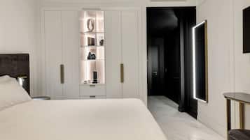 Une chambre moderne avec un grand lit, une armoire dotée d’étagères éclairées, une table de chevet et une commode.