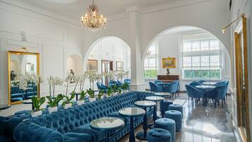 A luxurious room with a blue sofa, round tables, and a chandelier.