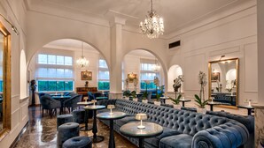 A luxurious lounge area with a large tufted sofa, round tables, and elegant chandeliers. - Majestic Palace Hotel (Sant'Agnello)