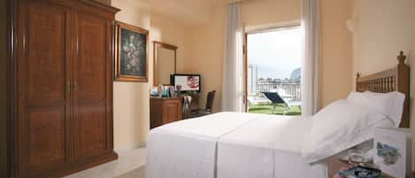Habitación de hotel con una cama grande, un escritorio con computadora, un armario y vistas al exterior.