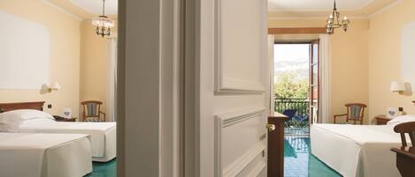 A hotel room with two beds, a balcony, and a view of the outdoors.