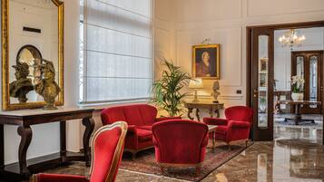 A spacious lobby with a red sofa, a large mirror, and a chandelier.