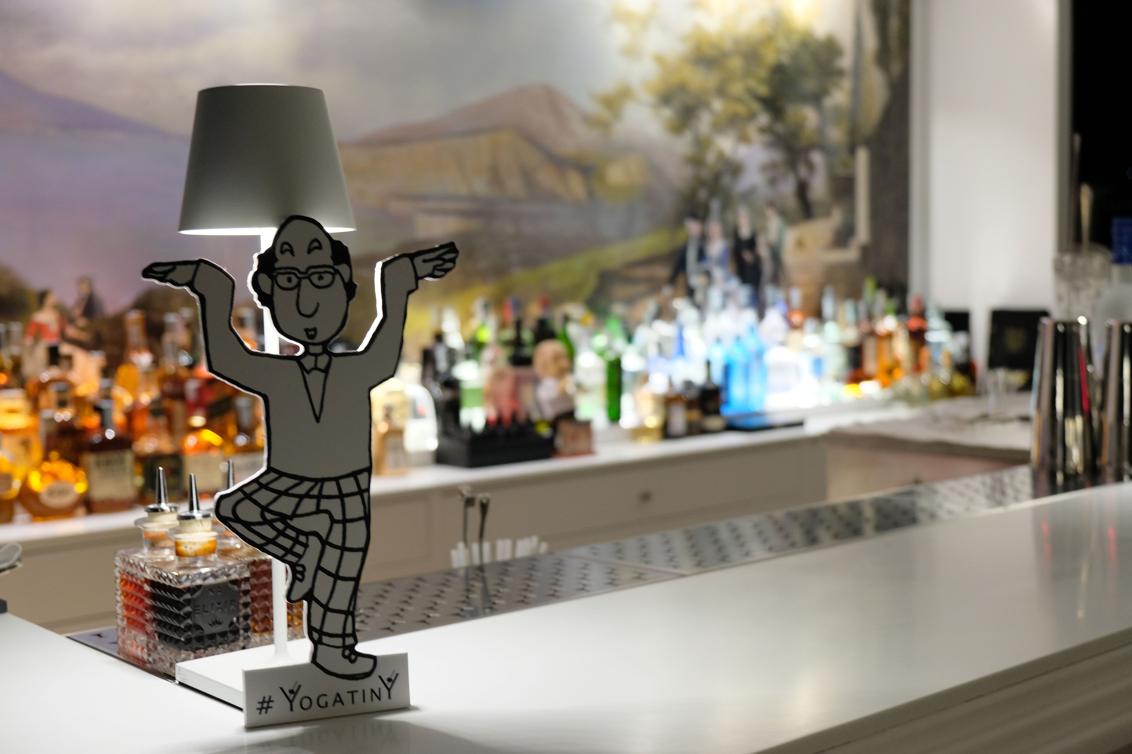 A bar area with a decorative figure, a glass display case, and a variety of bottles.