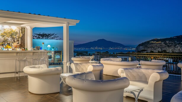 A rooftop bar with white leather sofas and a bar area with stools. - Majestic Palace Hotel (Sant'Agnello)
