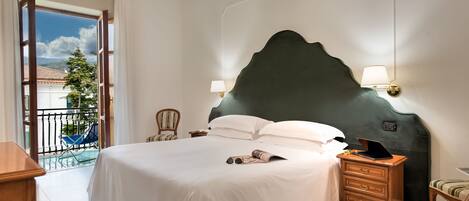 A spacious bedroom with a large bed, a nightstand with a lamp, a chair, and a view of the outdoors.