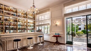 A bar area with shelves of bottles, a chandelier, and a view of the outside. - Majestic Palace Hotel (Sant'Agnello)