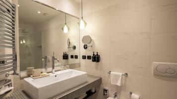 Une salle de bain moderne avec un grand lavabo blanc, un miroir et deux lampes suspendues.
