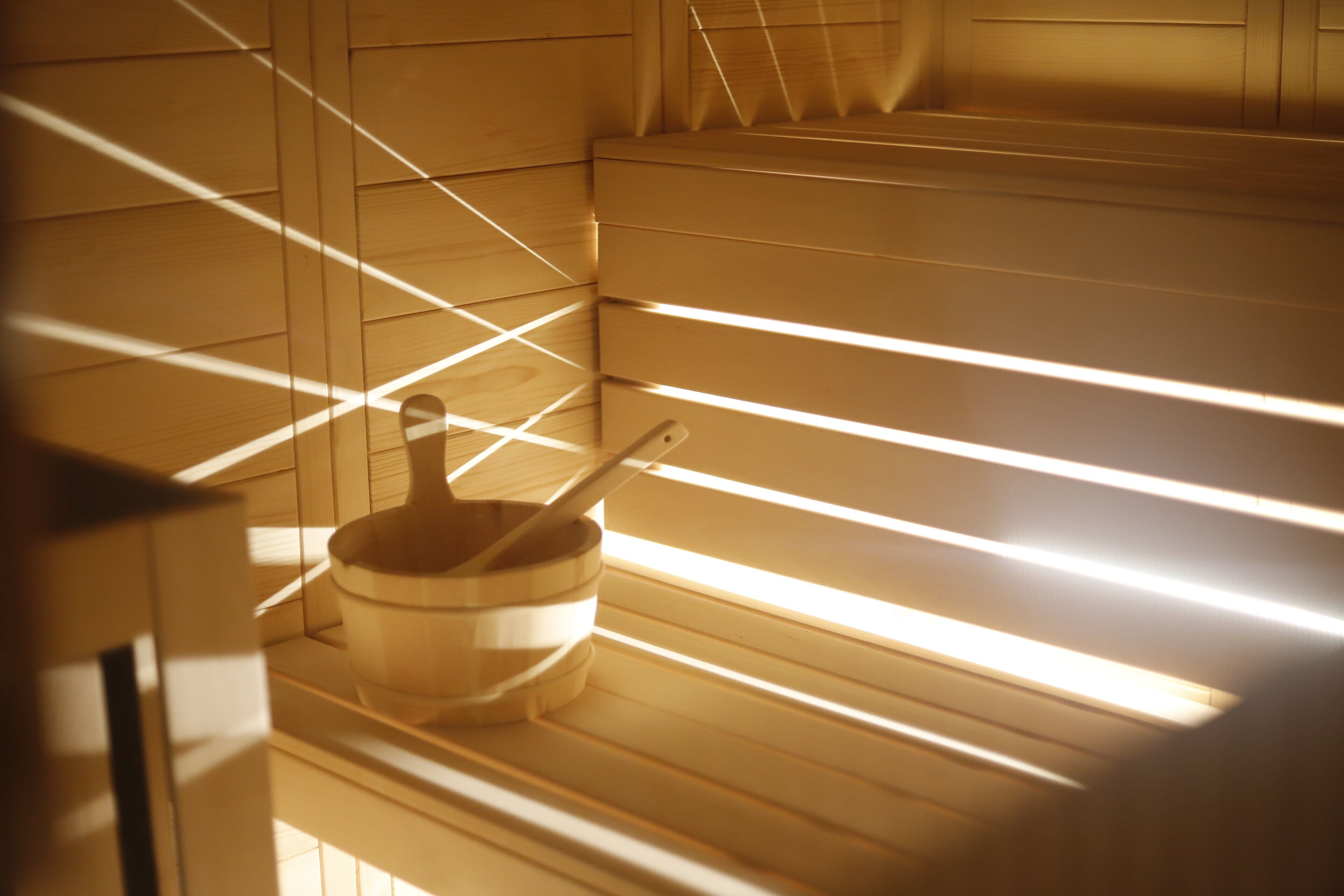 A sauna with wooden benches and a wooden bucket with a ladle.