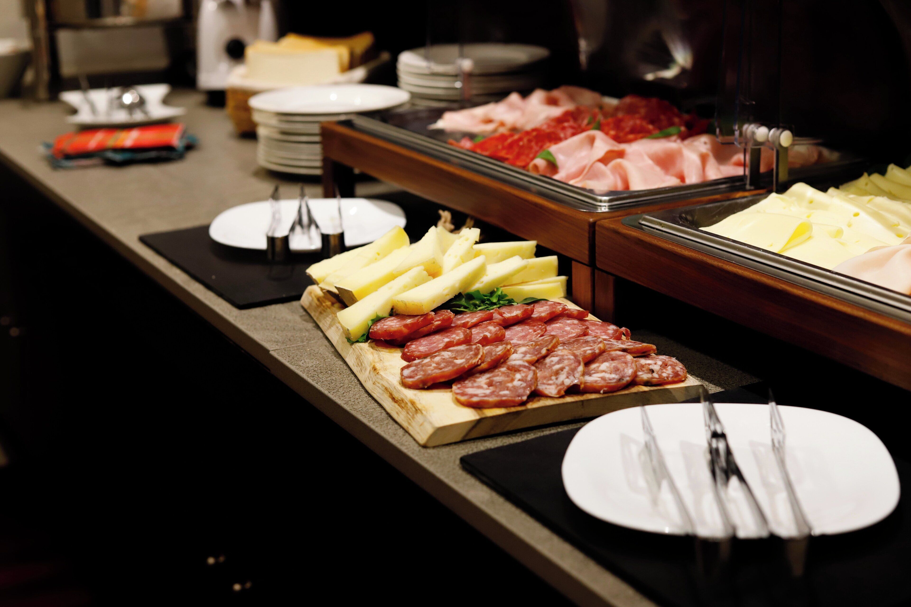 Un buffet con diverse pietanze tra cui salumi, formaggi e verdure.