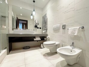 A modern bathroom with a large mirror, two sinks, a bidet, and a towel rack.