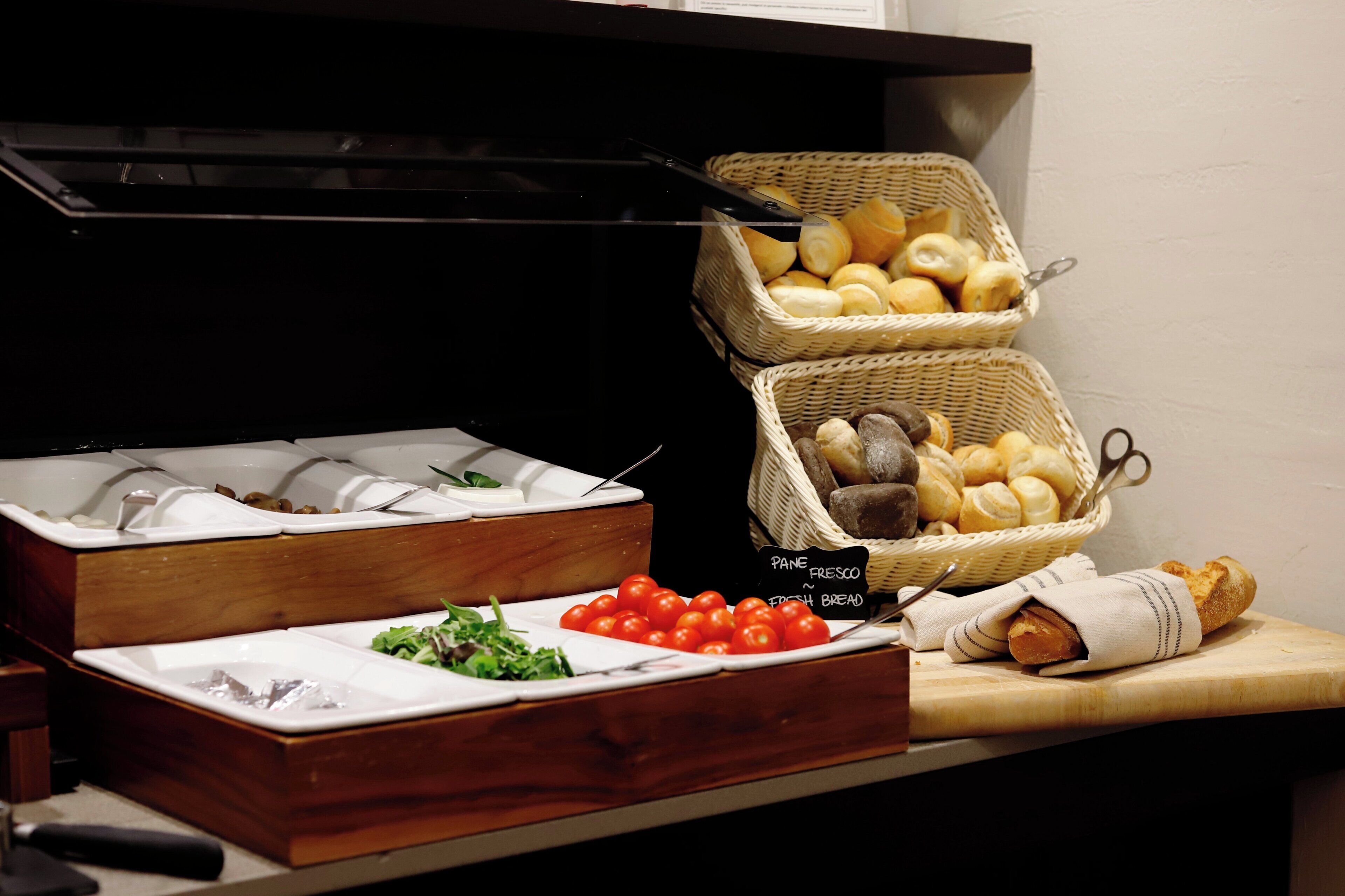 A buffet setup with bread baskets, a salad, and a sign indicating fresh bread.
