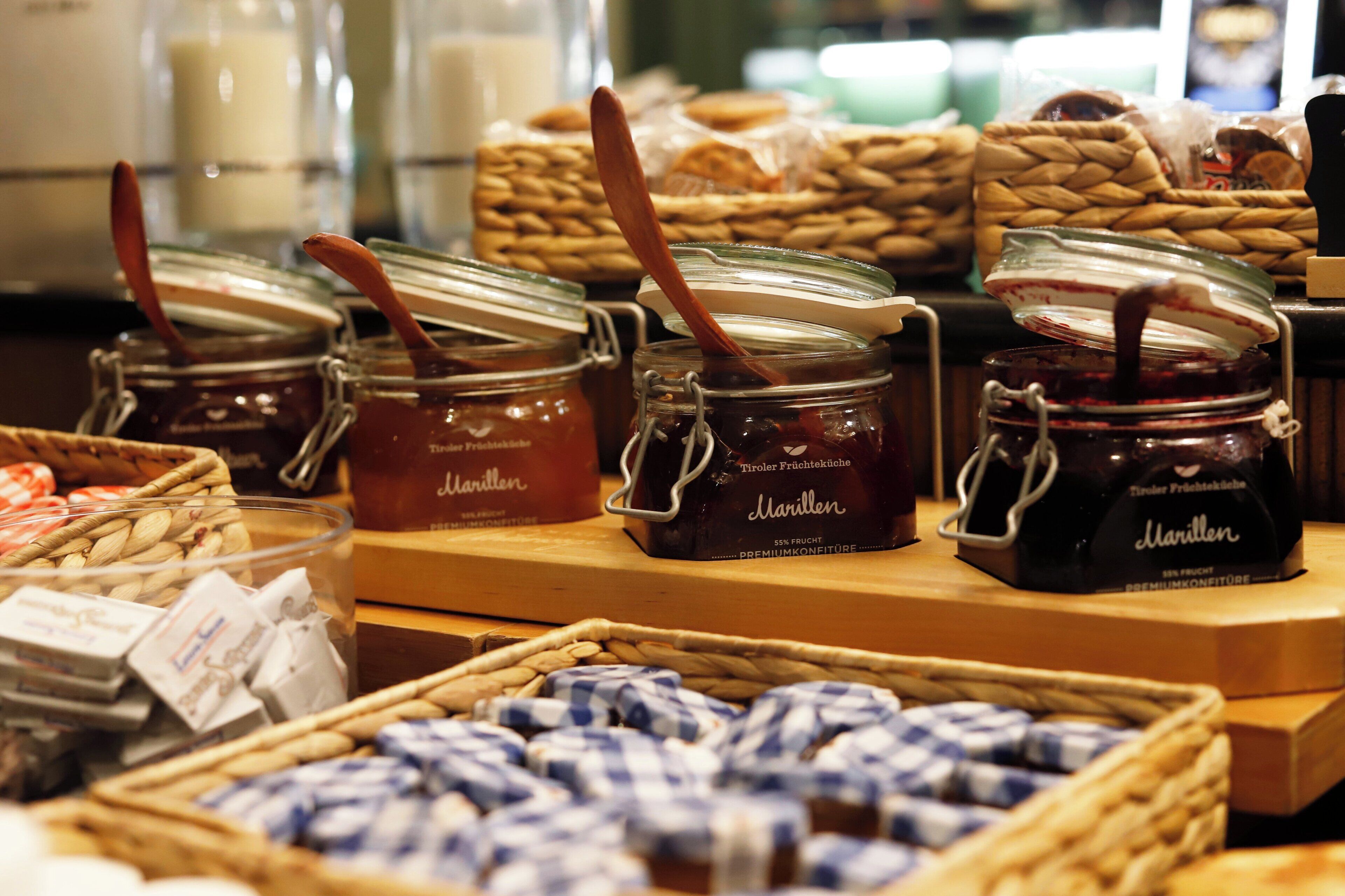 A display of jars with wooden spoons, labeled 'Marillen', and baskets of almonds and other nuts.