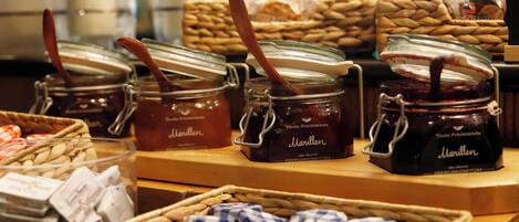 A display of jars with wooden spoons, labeled 'Marillen', and baskets of almonds and other nuts.