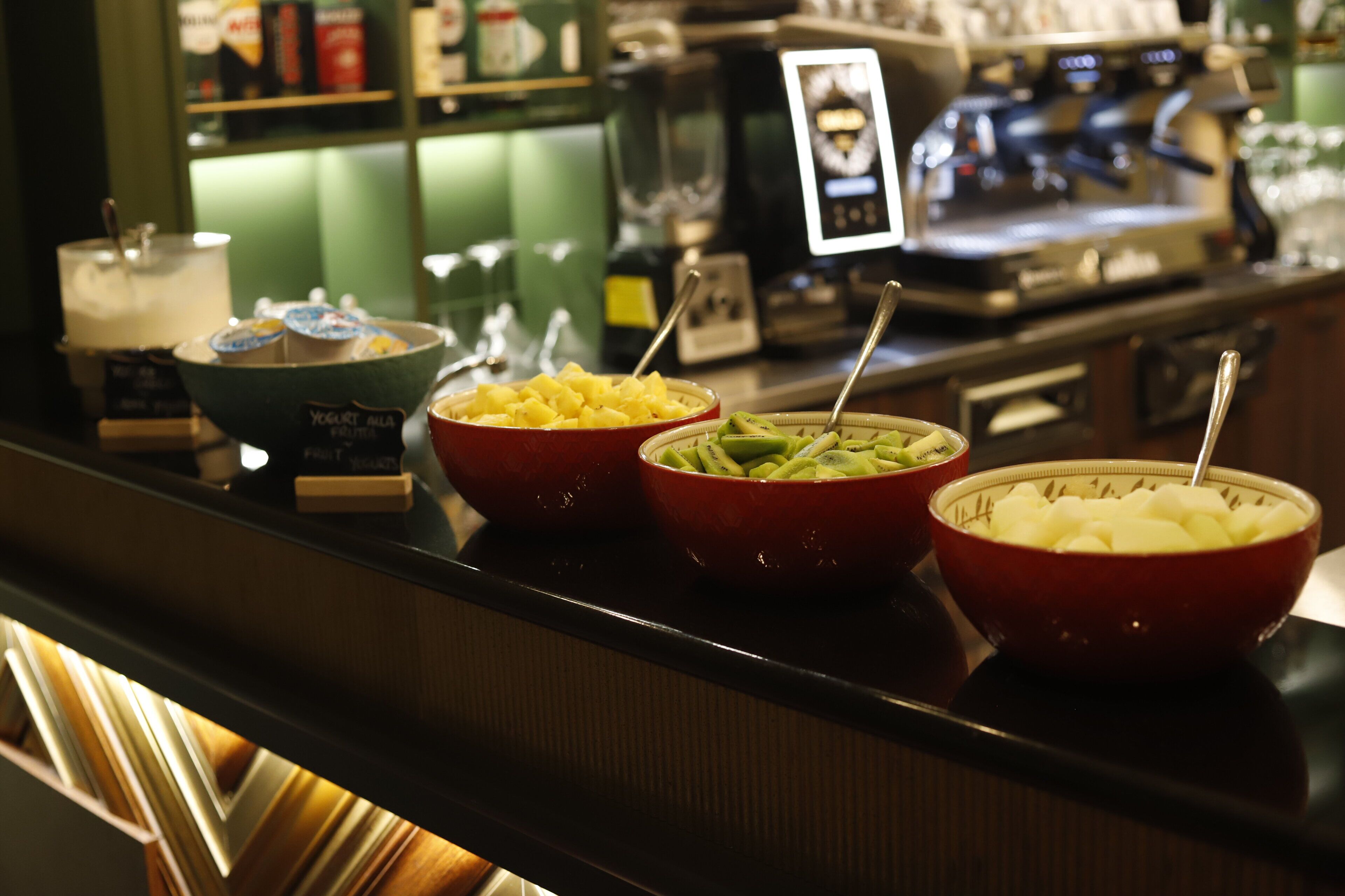 A buffet counter with bowls of fruit and yogurt parfaits.