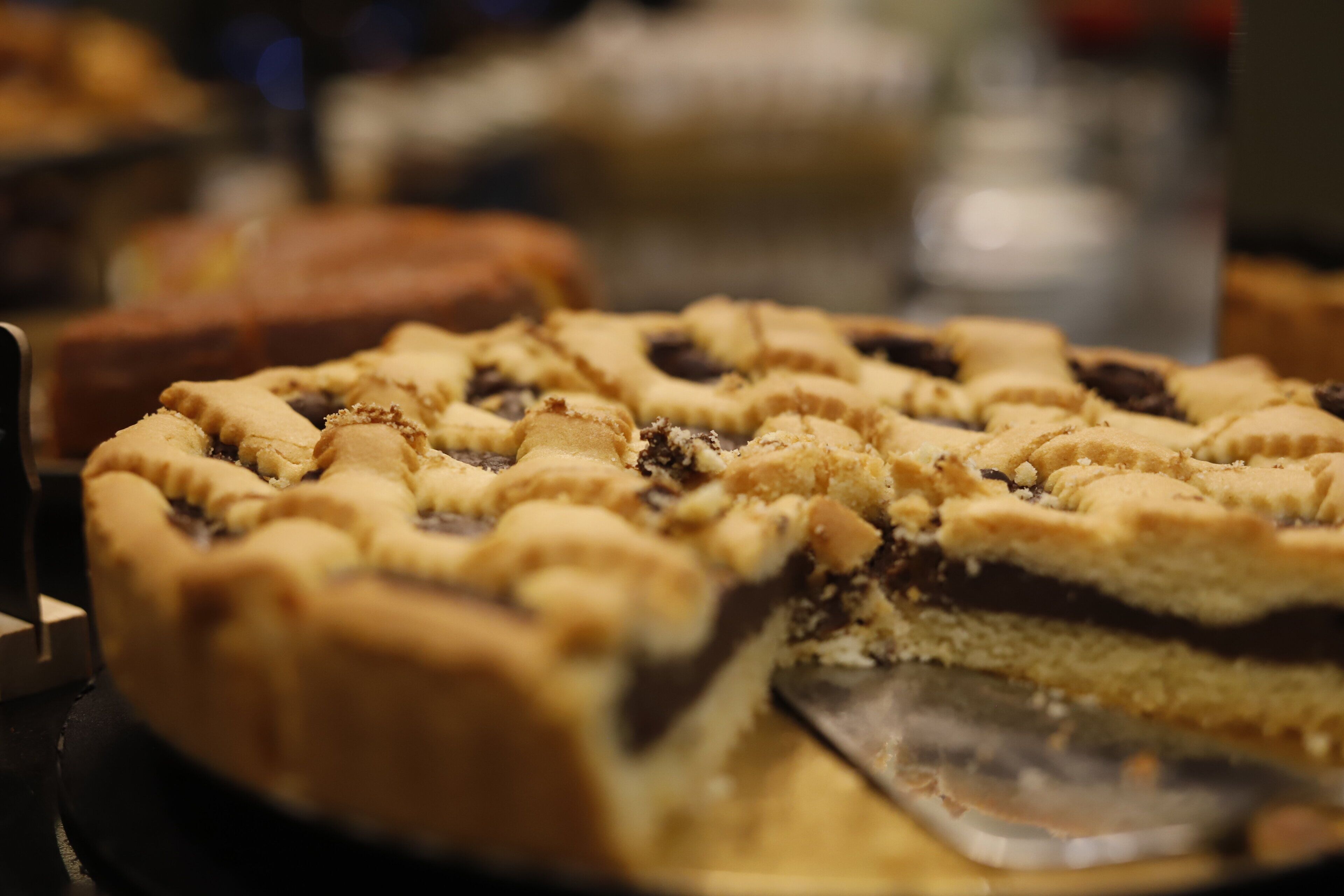 A pie with a lattice crust, partially sliced, on a serving tray.