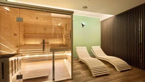 A sauna room with a glass enclosure, wooden benches, and a wooden wall with vertical slats. - Hotel Indigo Turin by IHG (Turin)