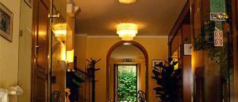 A hotel lobby with a reception desk, a chandelier, and a view of the greenery outside.