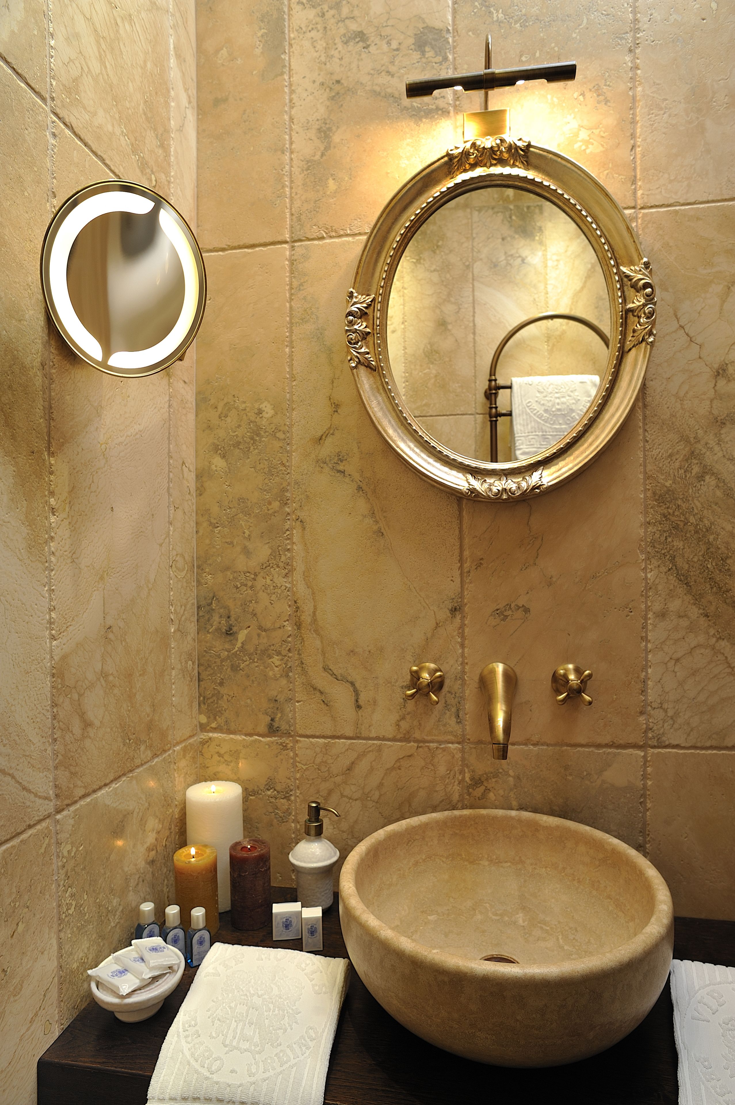Un bagno con un grande specchio rotondo, un lavandino tondo e un porta asciugamani.