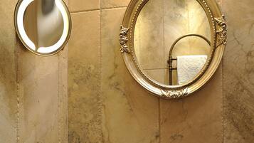Un bagno con un grande specchio rotondo, un lavandino tondo e un porta asciugamani.