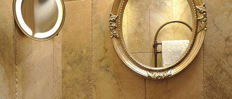 A bathroom with a large round mirror, a round sink, and a towel rack.