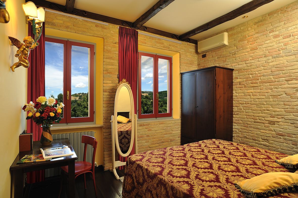Un dormitorio con cama, cómoda, tocador con espejo, escritorio con silla y ventana con cortinas.