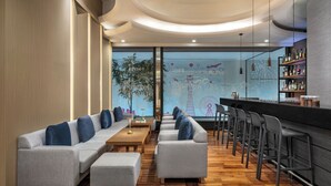 Un bar moderno con una barra larga, taburetes y un área de estar con sofás y una mesa de centro.