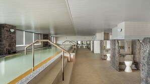 Un área de piscina interior moderna con vista despejada, una escalera y una fila de inodoros.