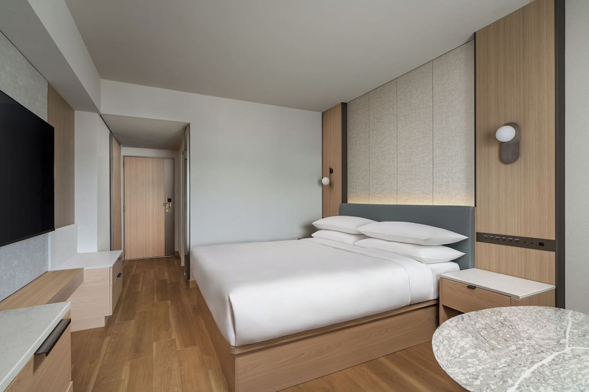 Una habitación de hotel moderna con cama, mesita de noche y televisor.