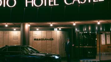 A hotel entrance with a sign reading "HOTEL CASTLE" and a black car parked in front.