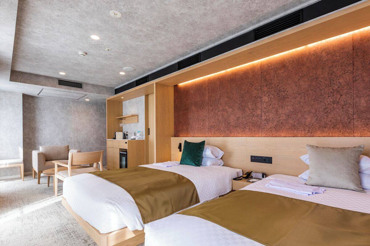 A hotel room with two beds, a desk, and a chair.