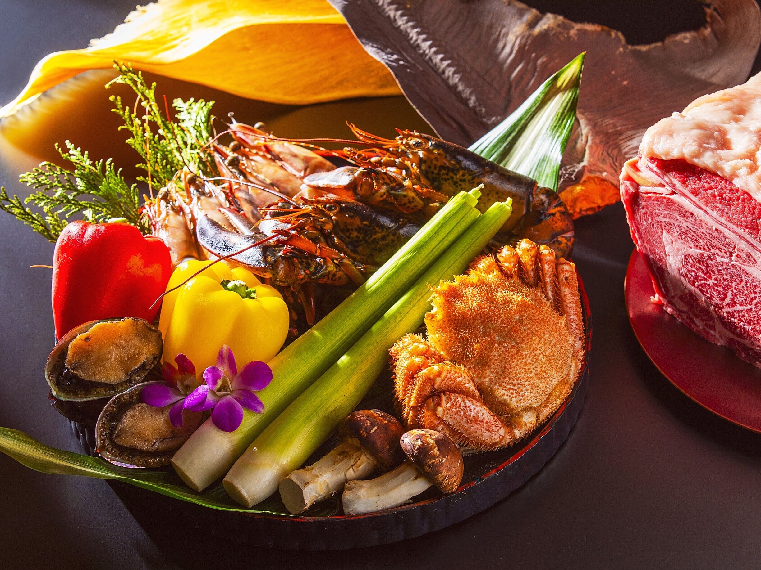 A seafood platter with lobster, scallops, and shrimp, accompanied by vegetables and herbs.