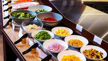 A buffet with various dishes including salads, vegetables, and grains.