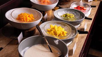 A buffet with various fruit options and a large bowl of a white creamy substance.