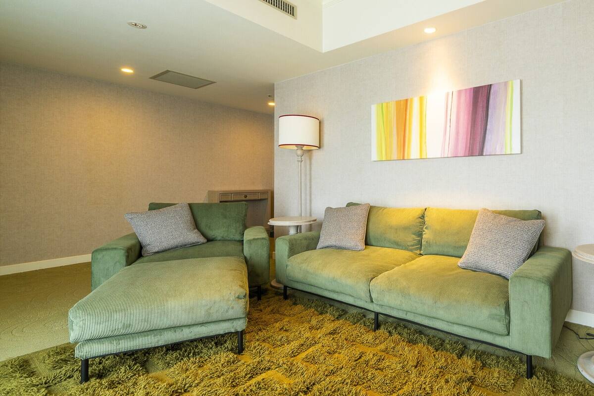 A modern living room with a green sofa, matching armchair, and a small round table.