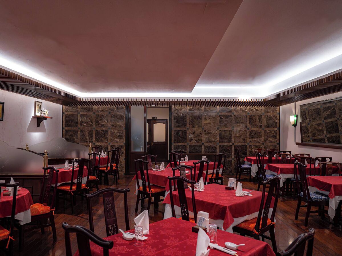 Un restaurante con varias mesas y sillas, una pared de piedra y un techo de madera.